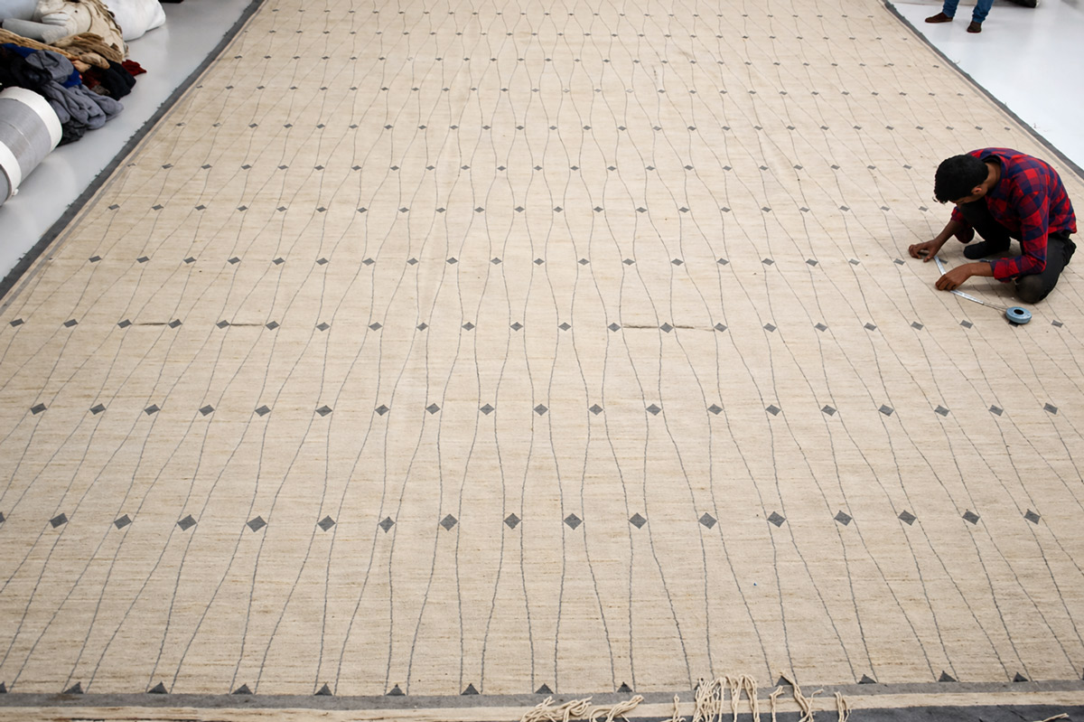 An artisan meticulously hand-knots Rani's custom rug.
